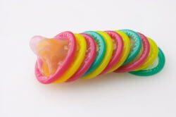 many colored condoms on white background