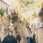 Protestors raising their arms in a crowd / Image: Unsplash