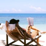 Woman reading books on a beach holiday