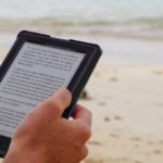 Person reading a kindle on beach holidays