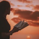 Girl reading against summer sunset