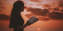 Girl reading against summer sunset
