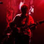 king krule on stage, red background, with a guitar