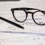 A pair of glasses and a pen resting on composition.