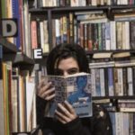 girl covering face with book - bookseller