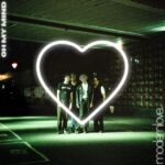 A photo of the Oh My Mind cover art. The band stand in the centre of the photo, there is a neon heart, and the image has a greenish tint to it
