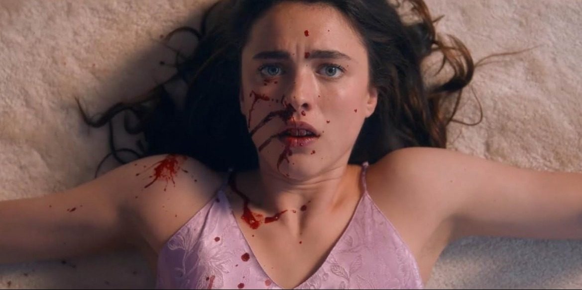 Close-up of a distressed, young, white, brunette female lying on her back on a cream carpet with splatters of blood across her face and upper body