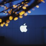 Building with Apple logo emblazoned on it. Tree with lights in the foreground.