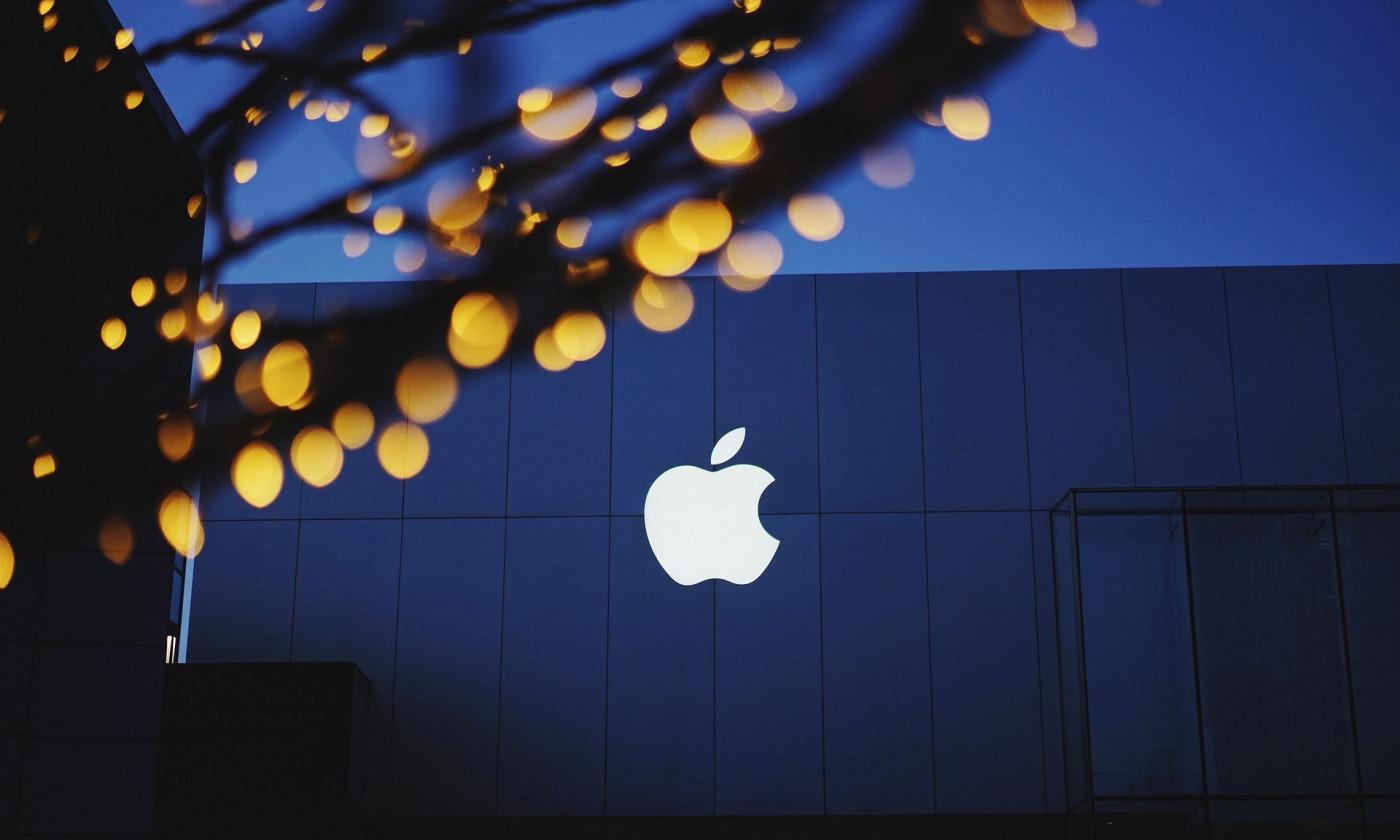 Building with Apple logo emblazoned on it. Tree with lights in the foreground.