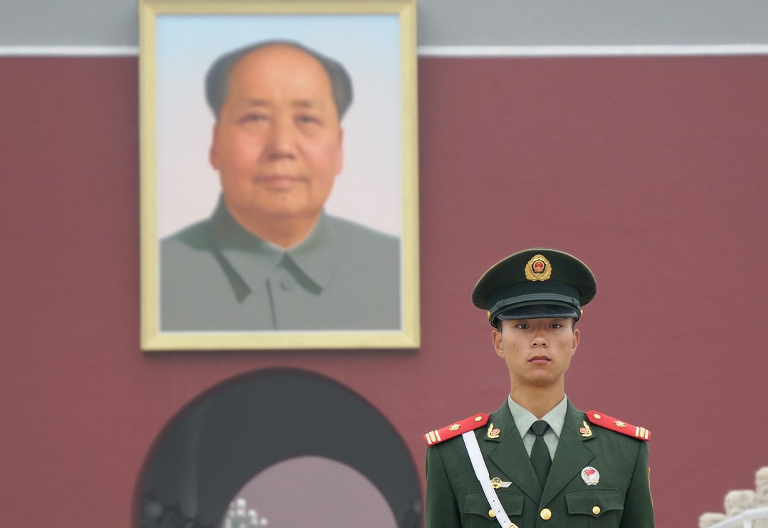 Chinese soldier guarding the southern entrance of the Forbbiden City in Beijing, dominated by a giant portrait of Mao Zedong.