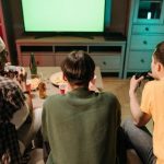 Three boys playing video games facing their backs towards us