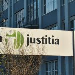 A white sign saying "Intrum Justitia" in front of an office building.