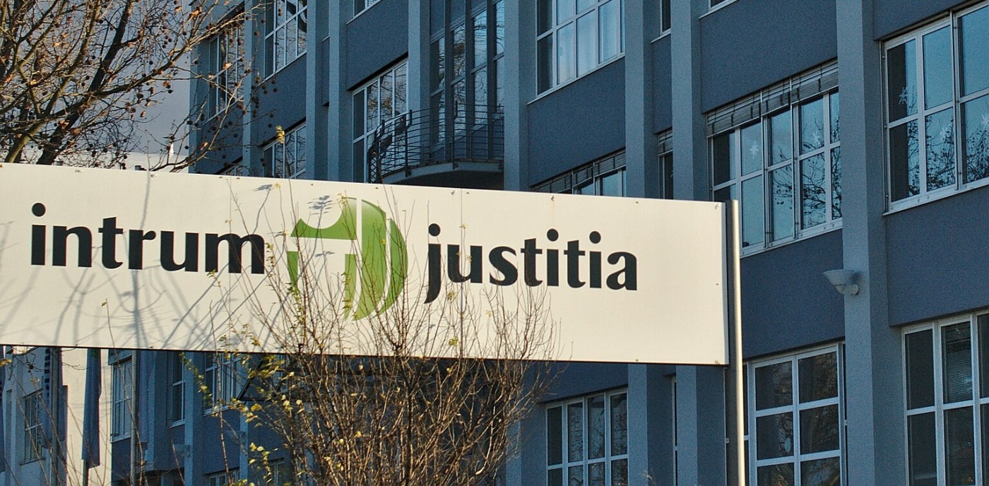 A white sign saying "Intrum Justitia" in front of an office building.