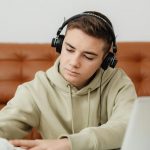 photo of boy doing homework while listening to music