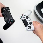 overhead shot of two people holding a black and white control each single handedly