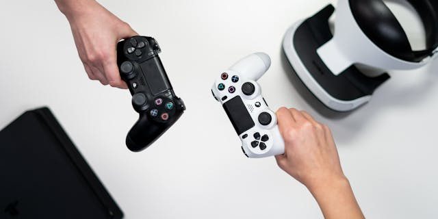 overhead shot of two people holding a black and white control each single handedly