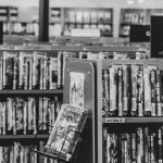 A black and white picture of a DVD shelves labelled by genre in a store