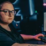 Woman sitting at gaming desktop, facing the camera