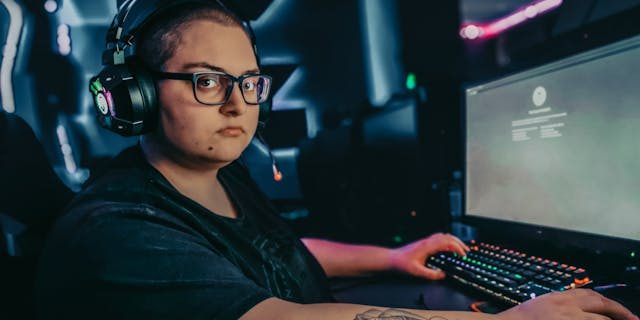Woman sitting at gaming desktop, facing the camera