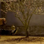 Two martial arts fighters face off in poses in front of a yellow leafed tree