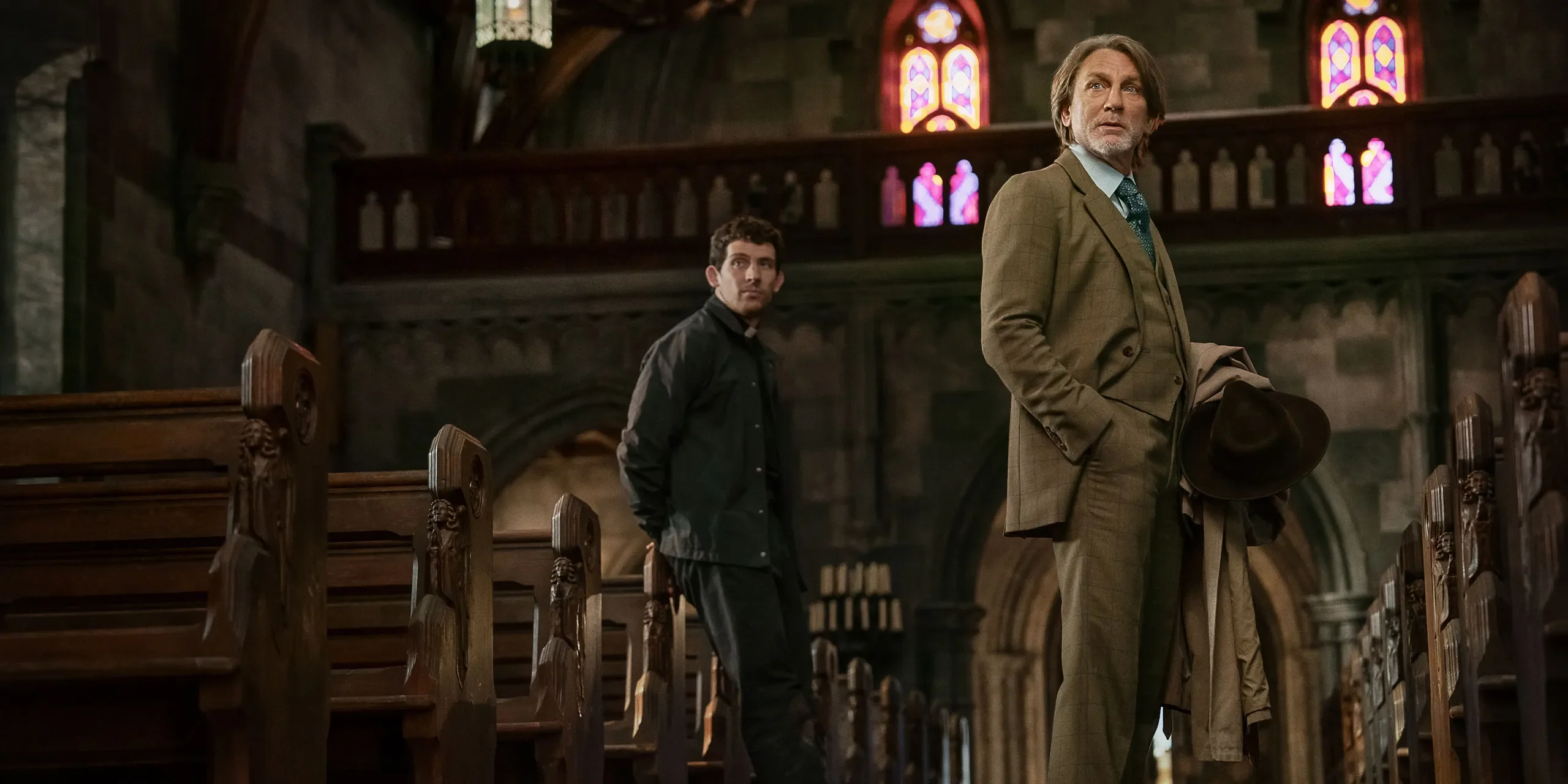 A detective and priest stand in the aisle of a grand church