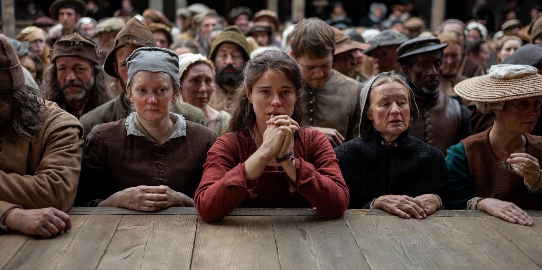 Jessie Buckley in Hamnet, stood in front of a stage