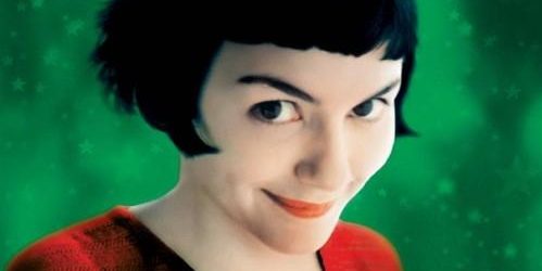 Film poster for Amélie featuring the main character smirking at the camera with a green background and yellow text